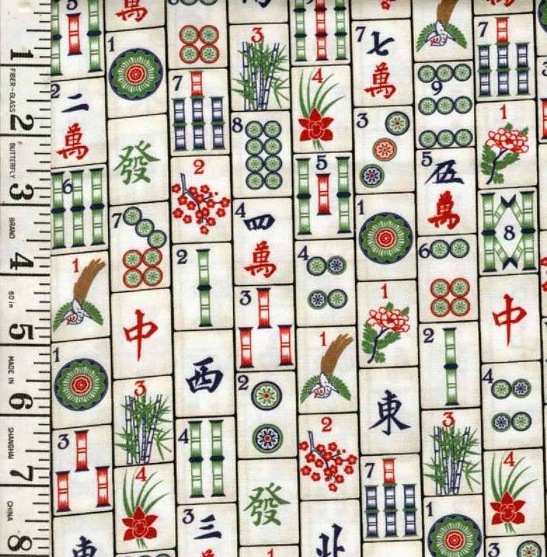 May include: A fabric featuring a repeating pattern of Mahjong tiles. The tiles are off-white with red, green, and black symbols and characters. A measuring tape is visible along the left side, marked in inches.