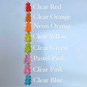 Pu&ograve; includere: Una disposizione verticale di ciondoli a forma di orsetti gommosi colorati. I ciondoli sono di colore rosso trasparente, arancione, arancione neon, giallo, verde, rosa pastello, rosa trasparente e azzurro. Il testo a destra elenca i colori.
