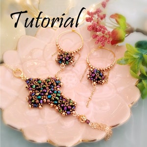 May include: A set of three gold-toned jewellery pieces with iridescent purple, green, and brown beads. The set includes a necklace, a pair of earrings, and a bracelet. The jewellery is displayed on a pink plate with a floral design.