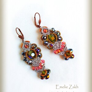 May include: A pair of handmade earrings with a gray crocheted design, featuring pink, green, and black beads. The earrings have a unique, intricate design and are accented with iridescent crystals.