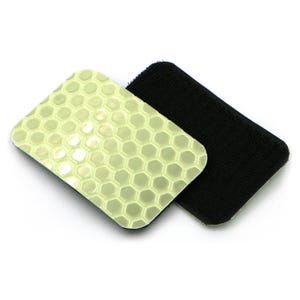 May include: Two wristbands: one black, absorbent terrycloth, and one with a pale green, honeycomb-patterned surface. The honeycomb pattern has a reflective, glossy appearance. The wristbands are likely for sports or fitness activities.