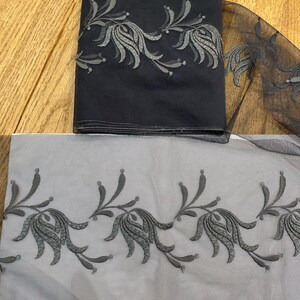 May include: Black tulle fabric with a grey floral embroidery design. The fabric is folded in half and the embroidery is visible on both sides.