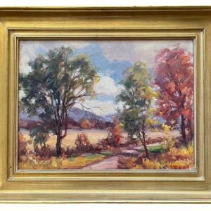 May include: An oil painting in a gold-toned frame depicting a landscape with trees in shades of green, yellow, and red. The scene features a path leading through a field toward distant hills under a cloudy sky. The artist's signature is in the corner.
