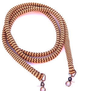 Könnte beinhalten: Ein braunes und beigefarbenes geflochtenes Seilhalfter mit silbernen Metallschnapphaken.