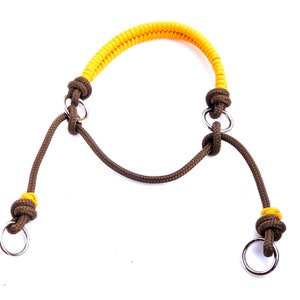 May include: A brown and yellow rope dog collar with two metal rings. The collar is made of braided rope with a yellow section in the middle.