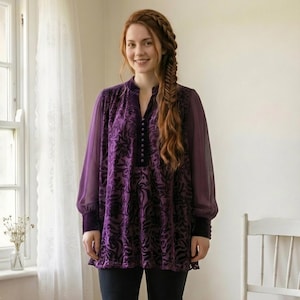 May include: A purple tunic with a floral pattern and long, sheer sleeves. The tunic has a high collar and a row of buttons down the front. The sleeves have dark purple cuffs. The model is wearing black pants.