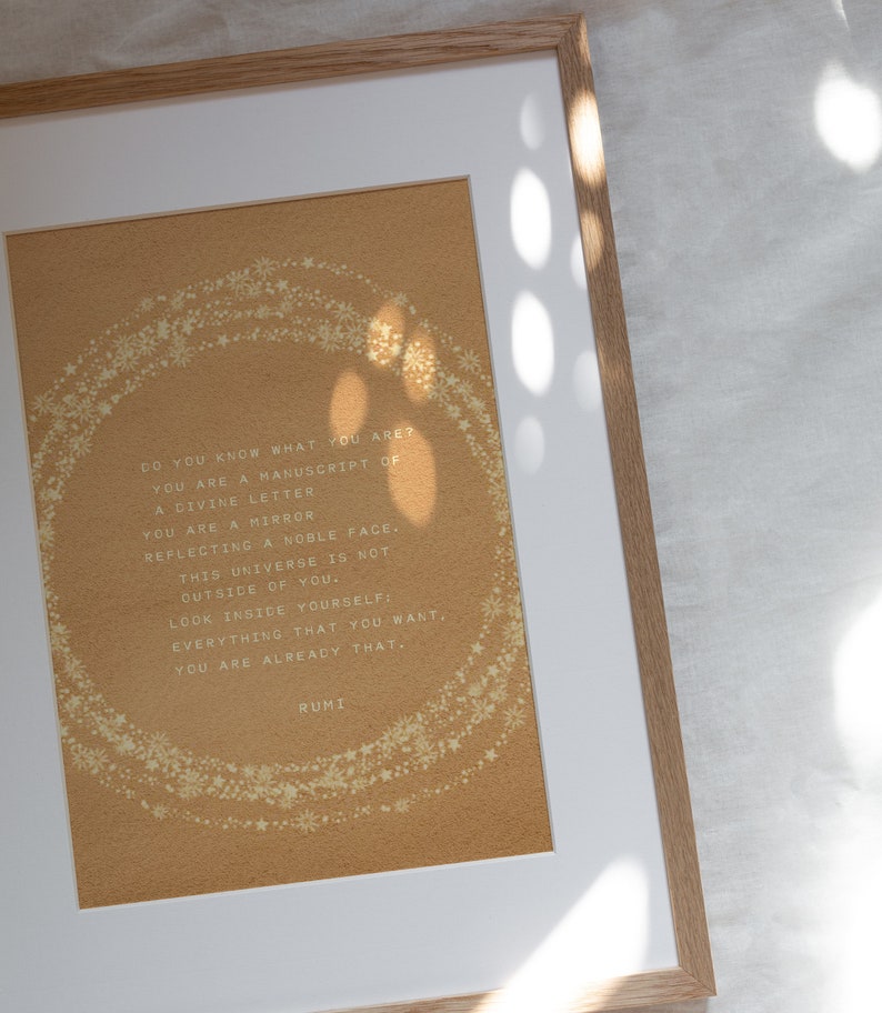 May include: A framed print with a gold background and white text. The text reads: "DO YOU KNOW WHAT YOU ARE? YOU ARE A MANUSCRIPT OF A DIVINE LETTER YOU ARE A MIRROR REFLECTING A NOBLE FACE. THIS UNIVERSE IS NOT OUTSIDE OF YOU. LOOK INSIDE YOURSELF: EVERYTHING THAT YOU WANT, YOU ARE ALREADY THAT. RUMI"