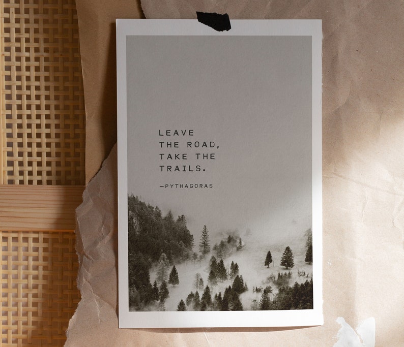 May include: A black and white print with a quote by Pythagoras: "Leave the road, take the trails." The print features a misty forest scene with trees and fog.
