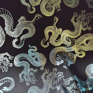 May include: A black fabric with a repeating pattern of silver dragons. The dragons are detailed with scales and have a slightly iridescent sheen.