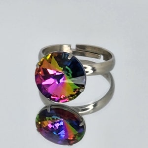 May include: A silver adjustable ring featuring a large, round, iridescent gemstone. The gemstone displays a rainbow of colours, including pink, orange, yellow, green, blue, and purple.