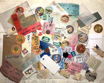 Op de afbeelding: Een verzameling vintage ephemera, waaronder tickets, postzegels, knopen en papieren items. De items zijn gerangschikt op een wit oppervlak, met een verscheidenheid aan kleuren en texturen. Sommige tickets lezen "ADMIT ONE" en "TICKET".