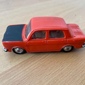 Può includere: Un'auto giocattolo rossa con un cofano nero e ruote argentate. L'auto è un modello vintage ed è in buone condizioni.