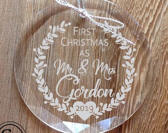 May include: Clear glass Christmas ornament with a white wreath design and the text "First Christmas as Mr & Mrs Gordon 2019".