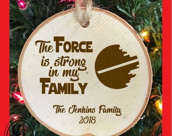 May include: A round wooden ornament with the text "The Force is strong in my FAMILY" and a brown Star Wars Death Star graphic. The ornament also includes the text "The Jenkins Family 2018".