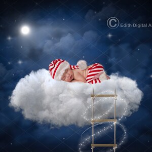 Op de afbeelding: Een baby in een rood-wit gestreept pakje en een kerstmanmuts slaapt op een pluche witte wolk. Een houten ladder met twinkelende lichtjes leidt naar de wolk.