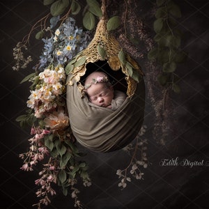 May include: A newborn baby is sleeping peacefully in a green fabric swaddle, nestled inside a delicate, crocheted, golden-brown nest. The nest is surrounded by lush, blooming flowers in shades of pink, white, and blue.