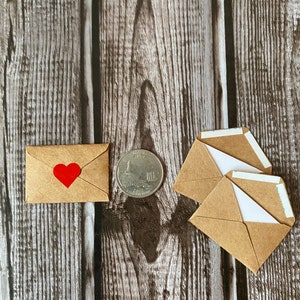 May include: Three small brown paper envelopes with white paper lining and a single envelope with a red heart on the front. A silver US quarter is also in the image.