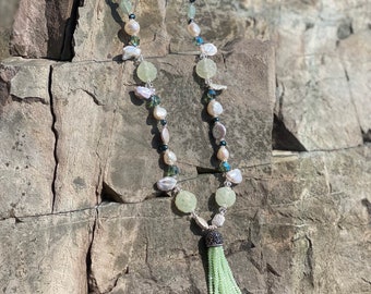 Green crystal tassel attached to beaded necklace.