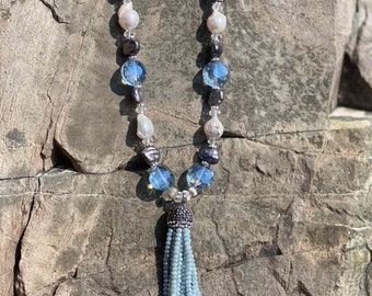 Tassel pendant attached to a beaded crystal and freshwater pearl necklace. 24”