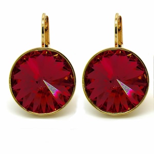 May include: A pair of gold earrings with red crystal stones. The earrings have a simple design with a round crystal stone hanging from a gold hook.