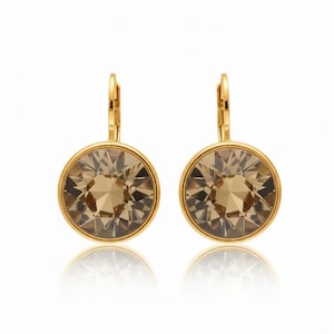 May include: A pair of gold-toned leverback earrings. Each earring features a large, round, faceted, light brown crystal set within a gold-colored bezel. The earrings are displayed against a white background.