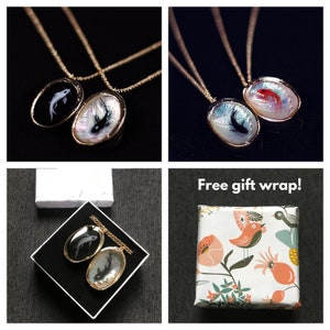 May include: Two gold necklaces with black and white fish pendants. The necklaces are displayed on a white surface with a white box. The text "Free gift wrap!" is displayed on a white background with a colorful floral pattern.