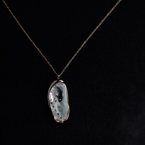 May include: A gold chain necklace with a white seashell pendant.