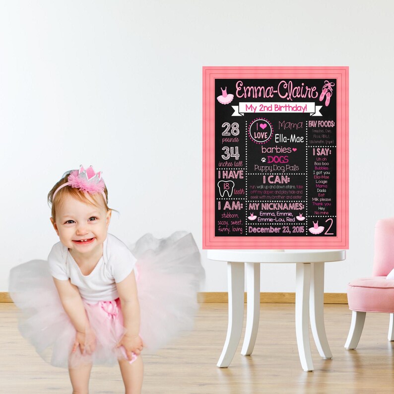 May include: A pink and black chalkboard sign with the text "Emma-Claire My 2nd Birthday!"  The sign lists the child's age, weight, height, favorite foods, and other details.  The sign is decorated with pink and white ballet shoes and a pink heart.