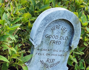 Puede incluir: Una lápida gris con la inscripción "Here Lies Good Old Fred. A Great Big Rock Fell On His Head. R.I.P."