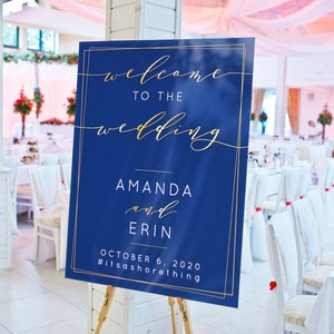 Puede incluir: Un cartel de boda azul con letras doradas que dice "Bienvenido a la boda de Amanda y Erin el 6 de octubre de 2020 #ItsAShoreThing".