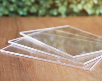 May include: Four clear acrylic sheets stacked on top of each other on a wooden surface.