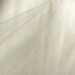 May include: White tulle fabric with a subtle sparkle. The fabric is sheer and has a delicate texture.