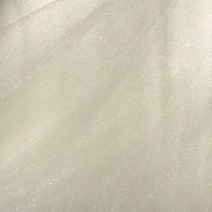 May include: White tulle fabric with a subtle sparkle. The fabric is sheer and has a delicate texture.