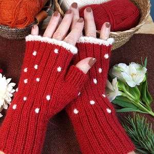 May include: A pair of red fingerless gloves with white polka dots. The gloves have a white trim around the wrist.