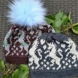 May include: Two knitted hats with different patterns. One hat is dark blue with a white pattern and the other is brown with a green and white pattern. The brown hat has a light blue pom-pom on top.