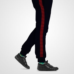 Può includere: Pantaloni della tuta blu navy con una striscia rossa lungo il lato. La striscia è composta da più linee rosse sottili.