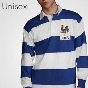 以下が含まれることがあります： 胸に雄鶏のロゴと「FRA」の文字が入った青と白のストライプのラグビーシャツです。
