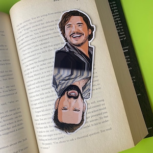 May include: A bookmark featuring a portrait of a man with a beard and a moustache. The bookmark is split in half, with the top half showing the man smiling and the bottom half showing the man with a serious expression. The bookmark is printed on a white background.