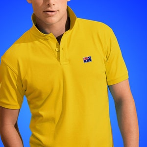 Könnte beinhalten: Ein gelbes Poloshirt mit einer kleinen australischen Flagge, die auf der linken Brust gestickt ist.