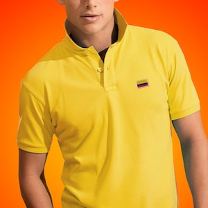 Peut inclure: Un polo jaune avec un petit drapeau colombien brodé sur la poitrine gauche.