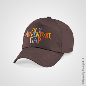 Op de afbeelding: Een bruine baseballpet met de tekst "MY ADVENTURE CAP" in kleurrijke letters.