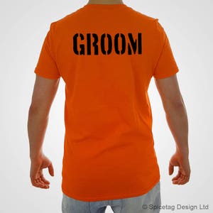 Puede incluir: Camiseta naranja con la palabra "GROOM" impresa en negro en la espalda.