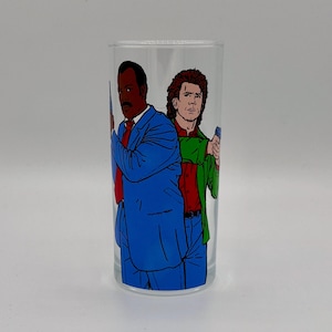 May include: Clear glass featuring a cartoon illustration of two men. One man is in a blue suit with a red tie, and the other is in a green jacket and red shirt. Both are holding a blue object.