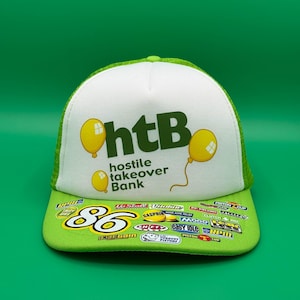 Può includere: Un cappellino trucker verde brillante e bianco con il testo "htB hostile takeover Bank" e grafiche di palloncini gialli sul pannello frontale. La visiera è coperta da vari loghi colorati di sponsor legati alle corse e il numero 86.