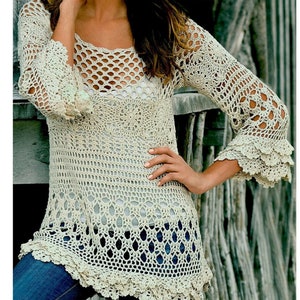 May include: A crocheted top with a delicate openwork design and a scalloped hem. The top is made with a light beige yarn and has long sleeves with a ruffled trim.