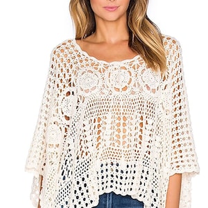 Puede incluir: Un top blanco de crochet con un corte holgado y fluido. El top tiene un delicado patrón de tejido abierto y un dobladillo ligeramente recortado.