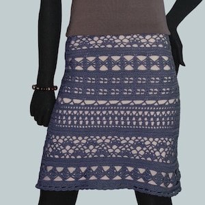 May include: A brown short-sleeved shirt with a V-neck and a crocheted skirt with a geometric pattern in shades of blue and white.