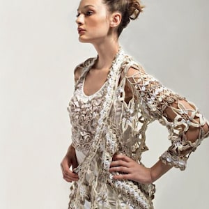 May include: A white crocheted cardigan with a delicate floral pattern. The cardigan has a loose fit and three-quarter sleeves.