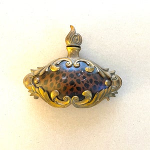 May include: A gold and brown decorative bottle with a leopard print design and ornate details.