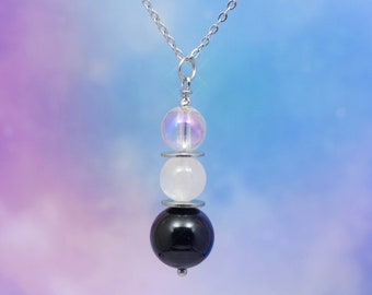 May include: A silver chain necklace with three beads: a clear iridescent bead, a white bead, and a black bead.